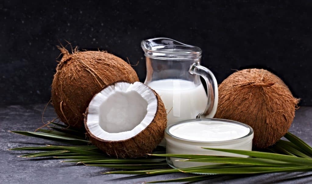 coconut milk in pitcher and whole coconuts