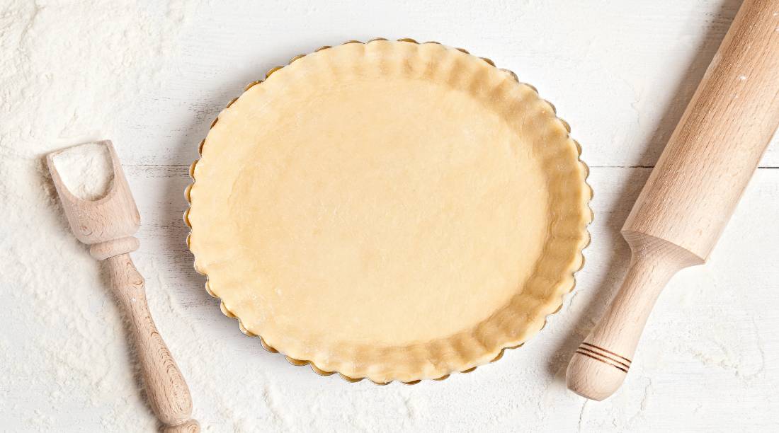 homemade pie crust in pie tin and rolling pin on table