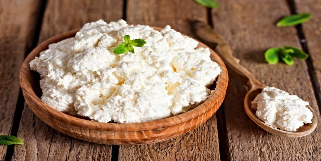 old wooden bowl of ricotta cheese on table