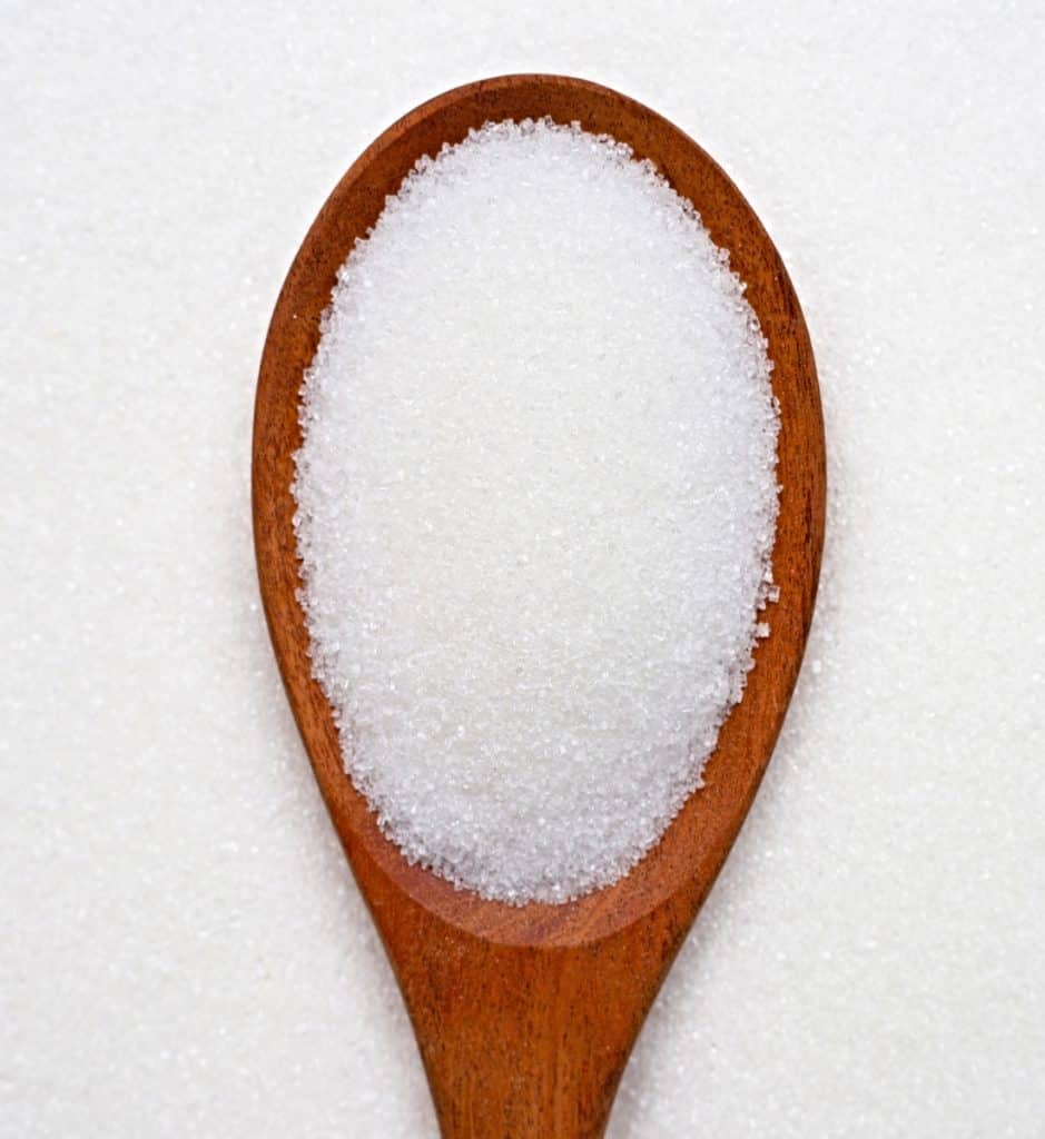 closeup of measuring spoon of granulated sugar