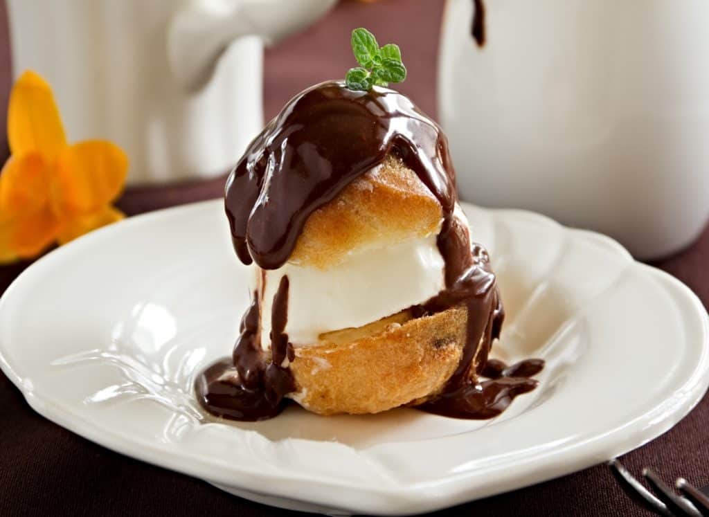 homemade cream puff with filling topped with chocolate ganache
