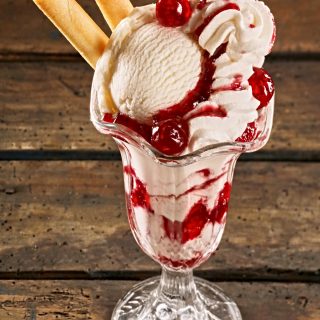 ice cream sundae with cherry sauce and vanilla sticks