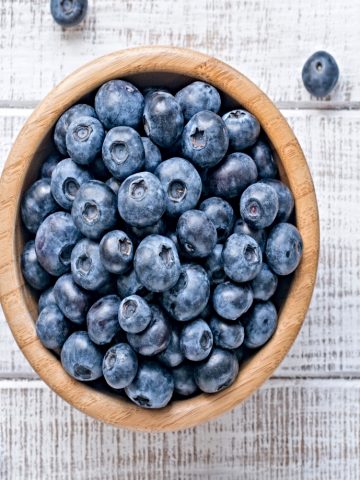 overhead picture of bowl of fresh blueberries in bowl on wooden table