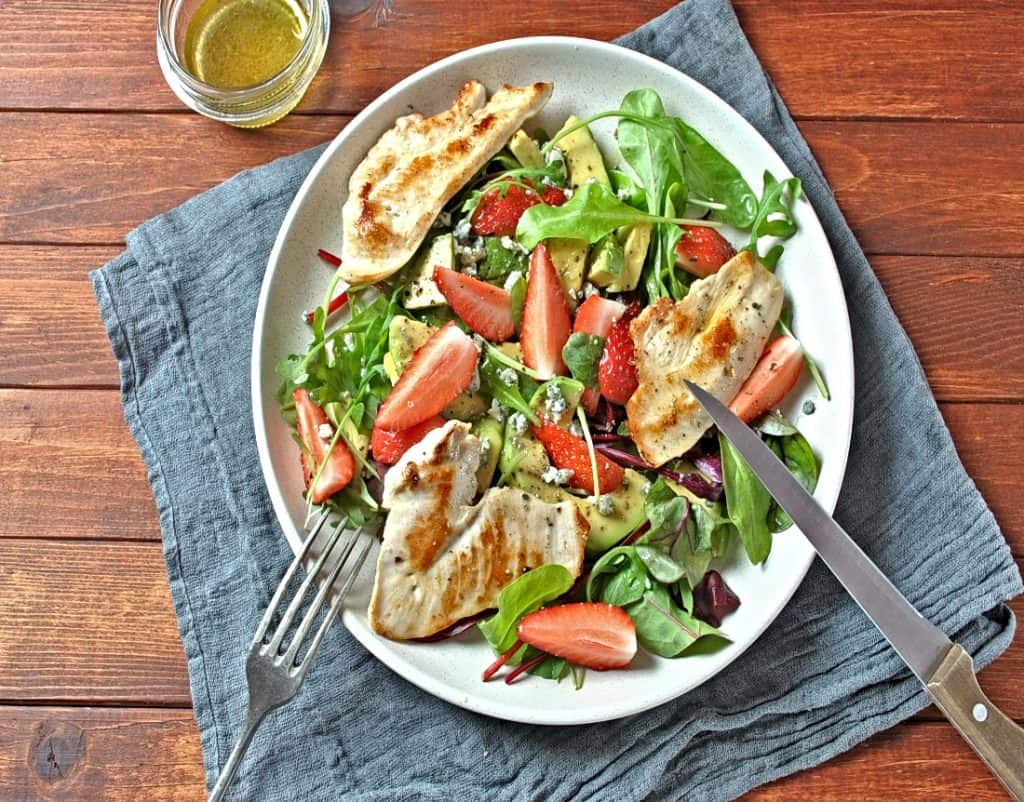overhead view of plate of chicken with avocado and strawberries