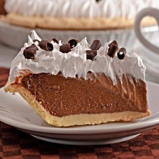 slice of homemade chocolate pie on plate with whipped cream and cocoa