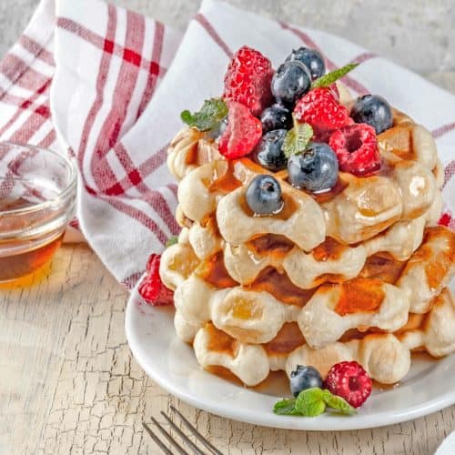 plate of homemade waffles made without milk topped with berries and maple syrup